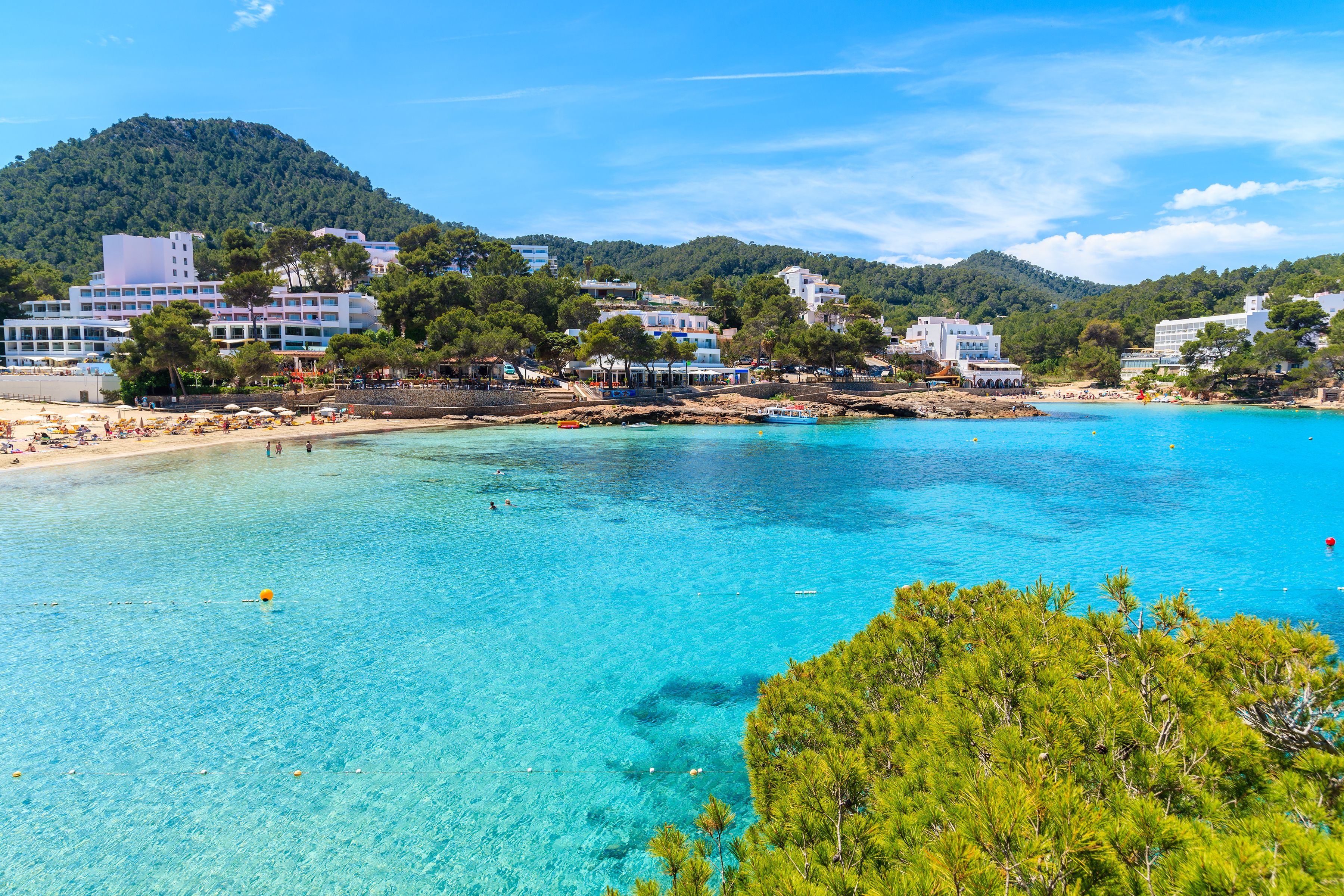 View of a tranquil bay with crystal-clear water with hotels along the coast in the background