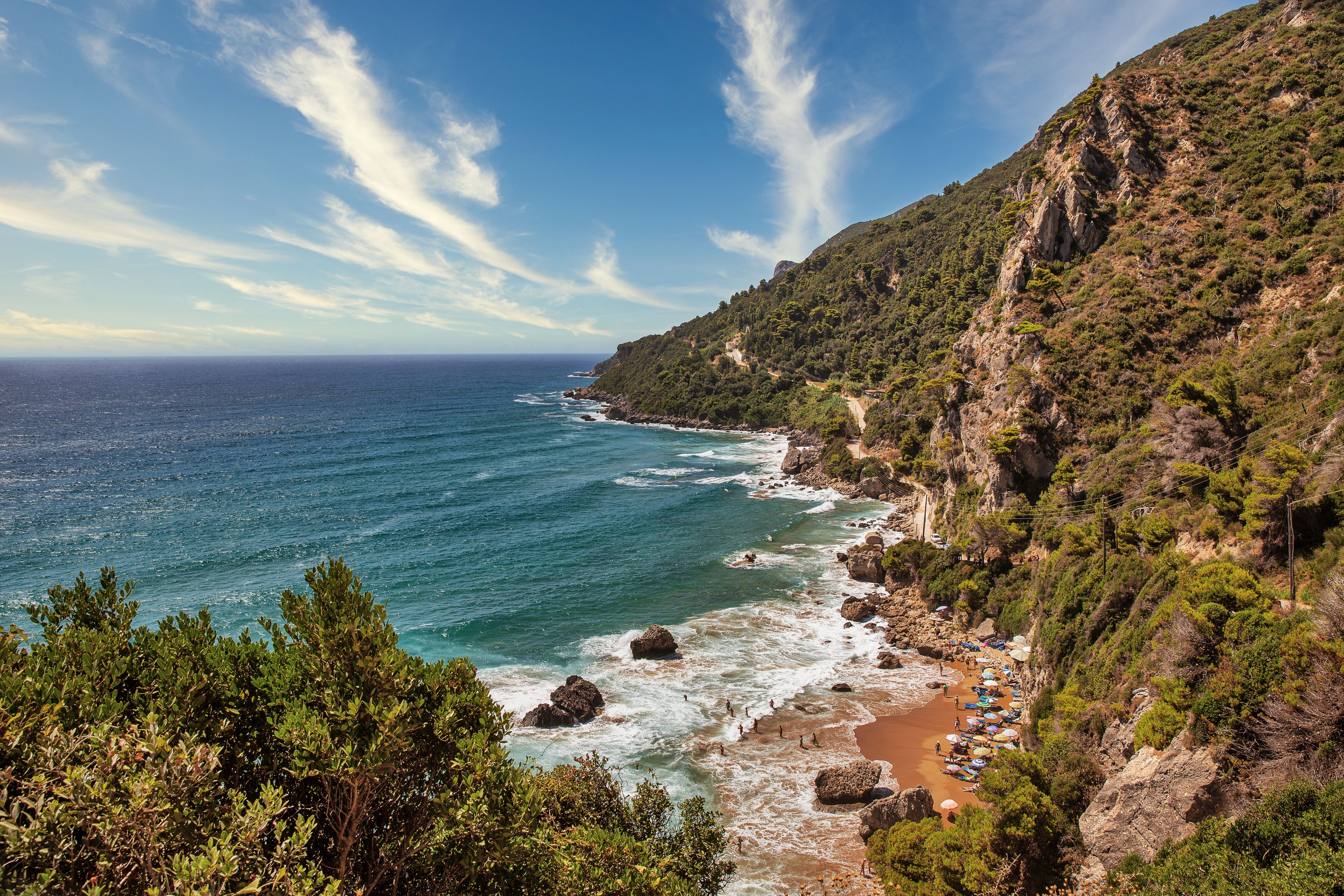 View of a small and secluded strip of sand that's surrounded by cliffs and lush greenery.