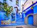 A vibrant blue staircase and wall decorated with colourful flowerpots in the town of Chefchaouen in Morocco
