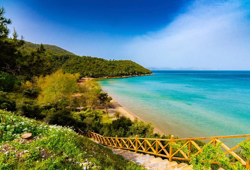 A view of Dilek Peninsula National Park in Turkey with coastal steps leading down to a small beach with bright turquoise sea