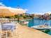 View of a cafe with shaded tables overlooking a bay with boats in Kefalonia