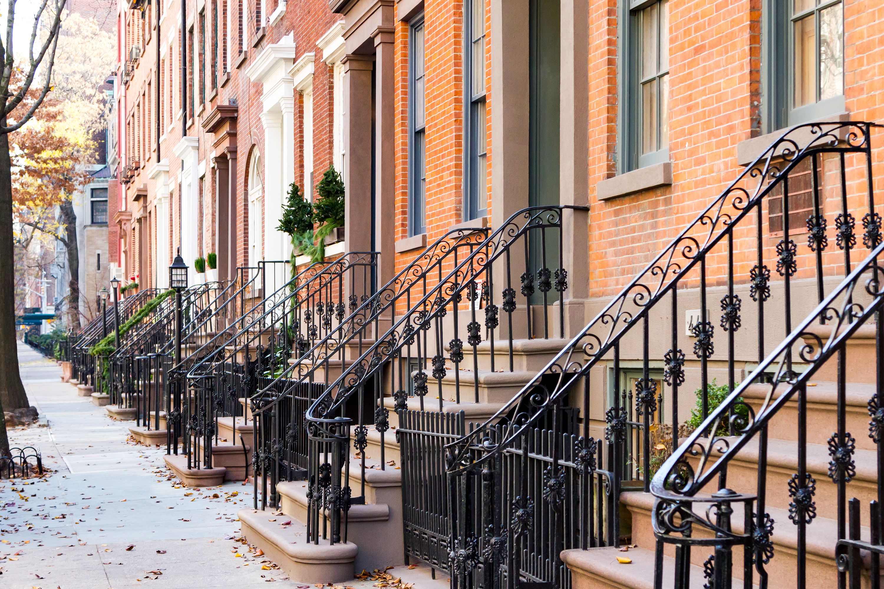 Row of old historic brownstone buildings along an empty sidewalk block in West Village, Manhattan, New York City