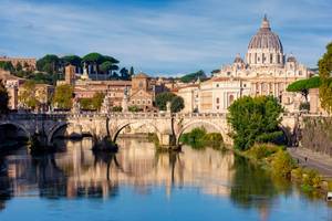 View across the River Tiber of the arched Victor Emmanuel II bridge and the huge St Peter's Basilica