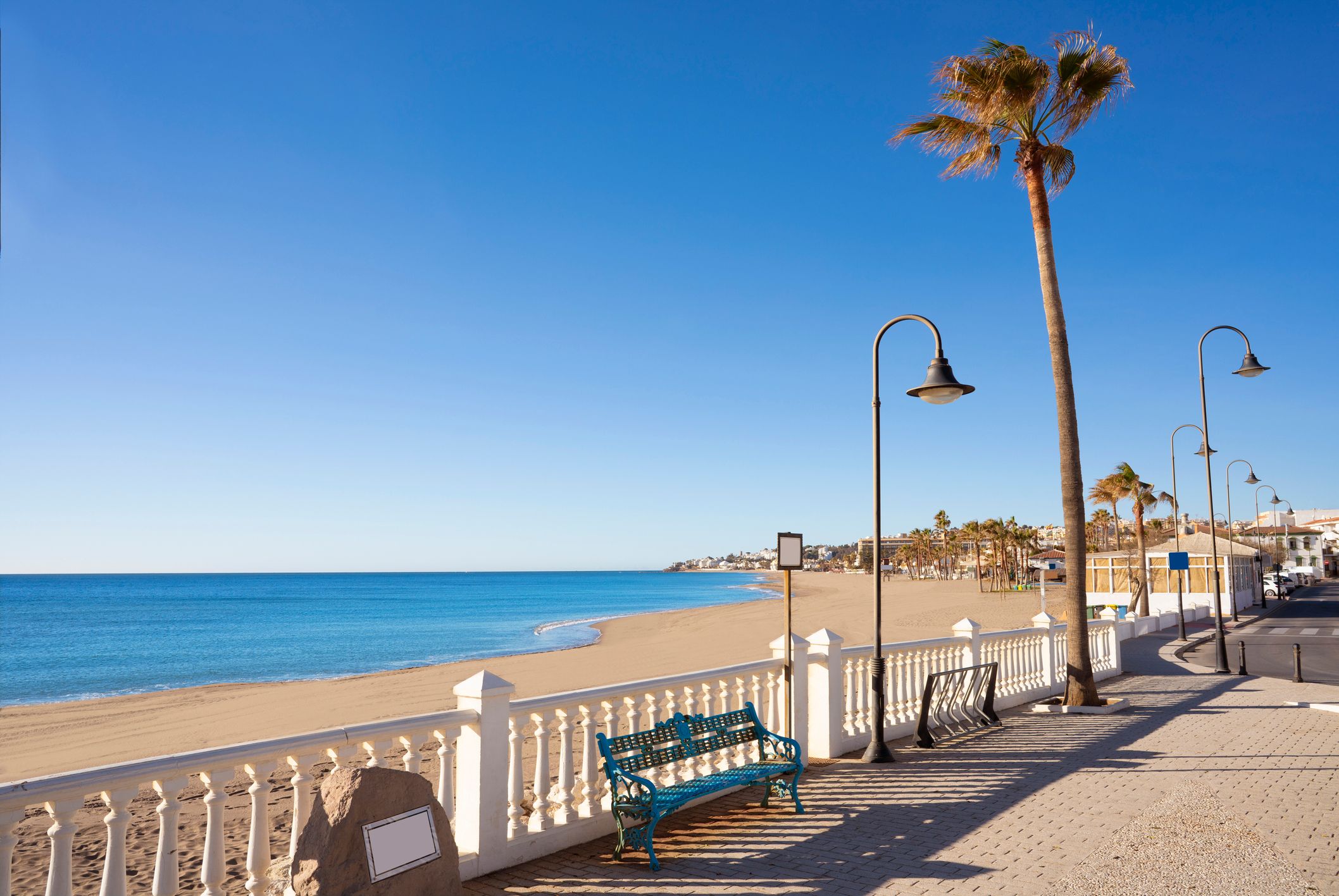 View across a palm-tree-lined promenade on to the pristine sandy shores of La Cala de Mijas