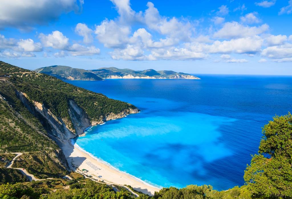 View on the turquoise waters and golden sands of Mytros Beach, surrounded by steep green cliffs