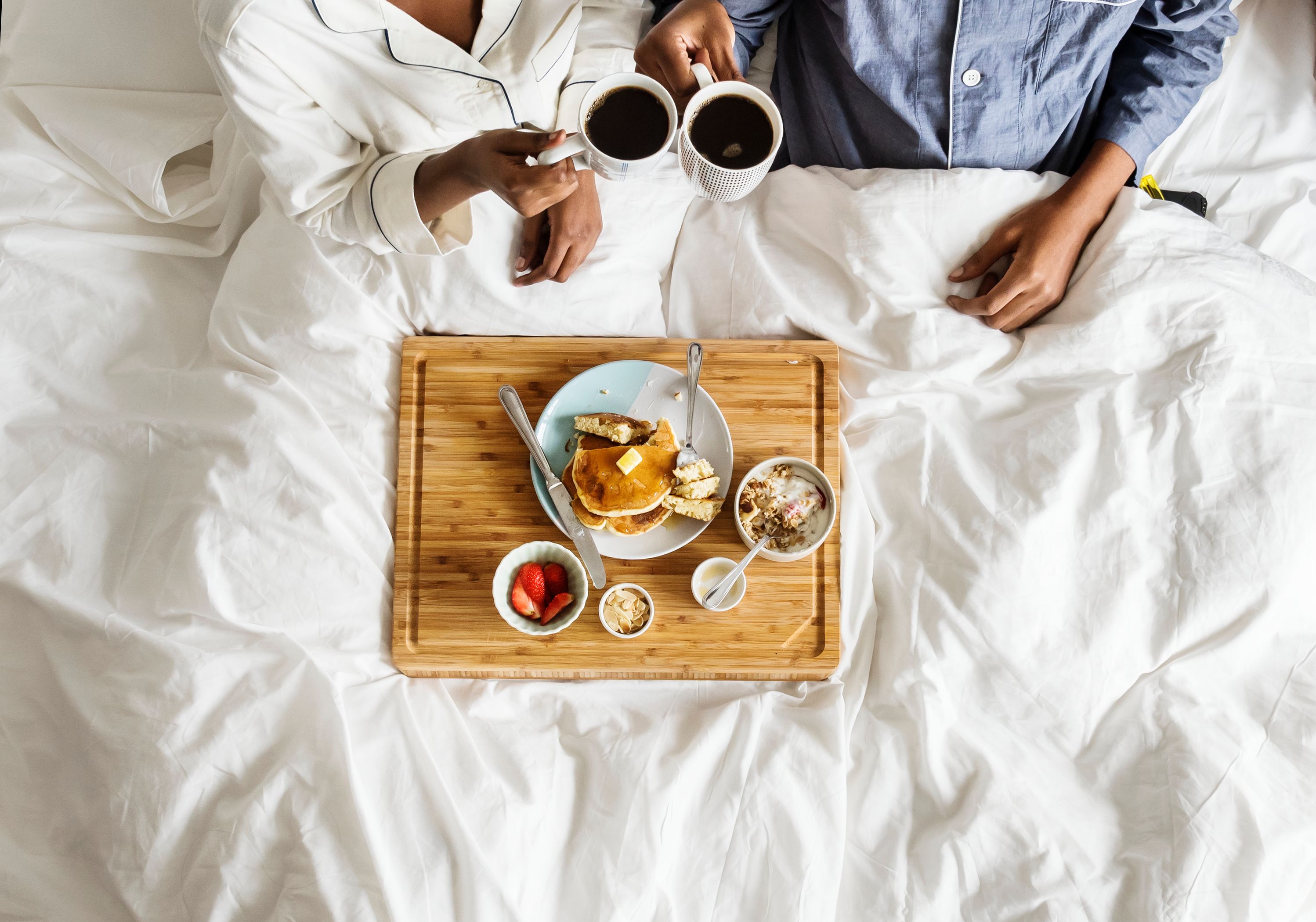 An aerial shot of a couple having a room-service breakfast in bed in a hotel