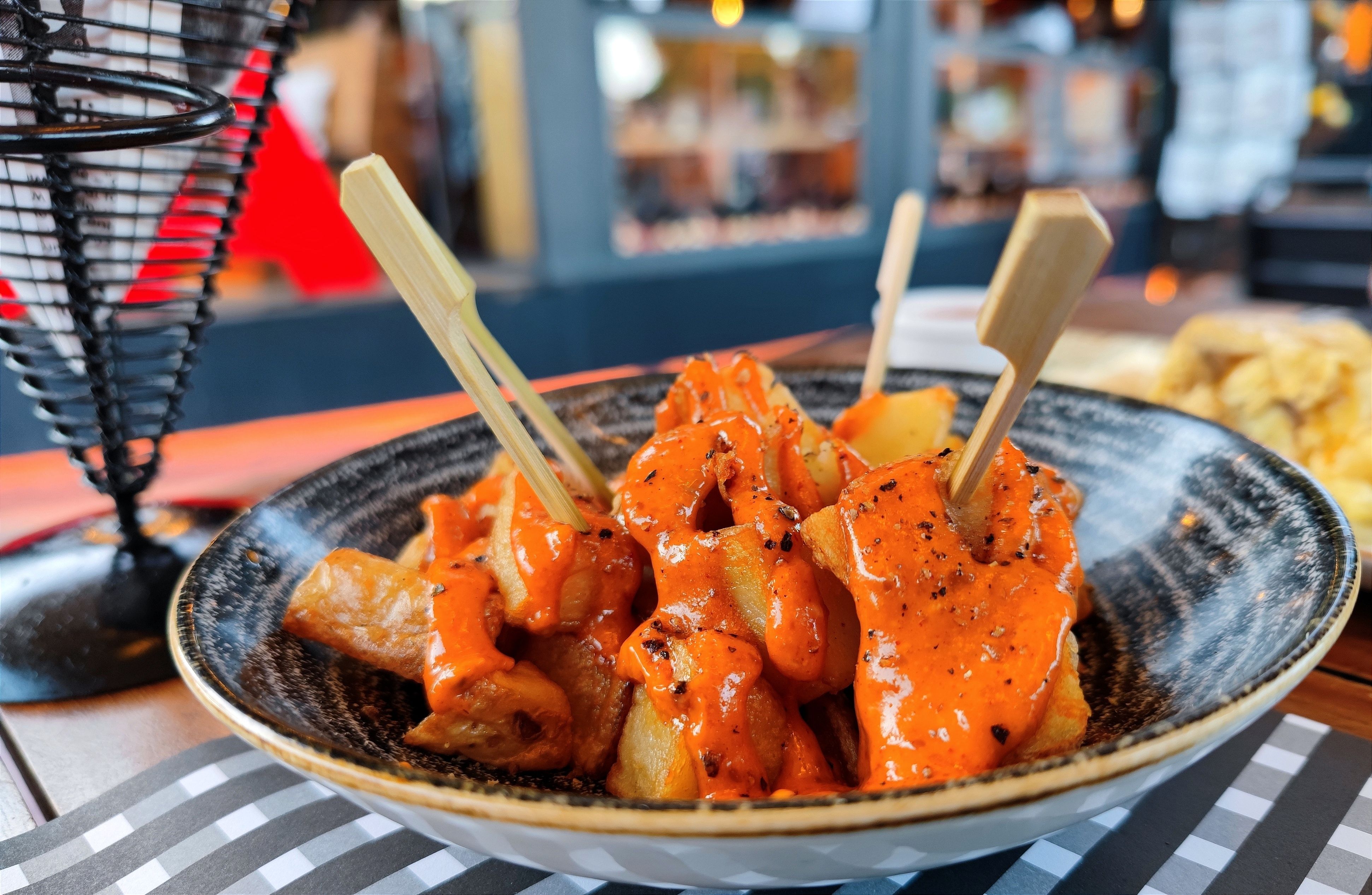 A dish of patatas bravas with spicy orange sauce served in a restaurant
