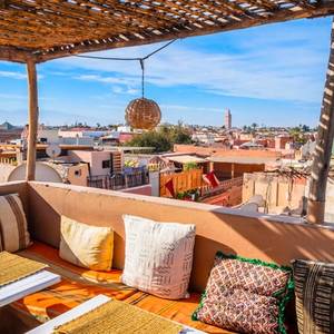 Colourful cushions along the benches of a traditional rooftop cafe in Marrakech, which has views of the city's flat-roofed houses