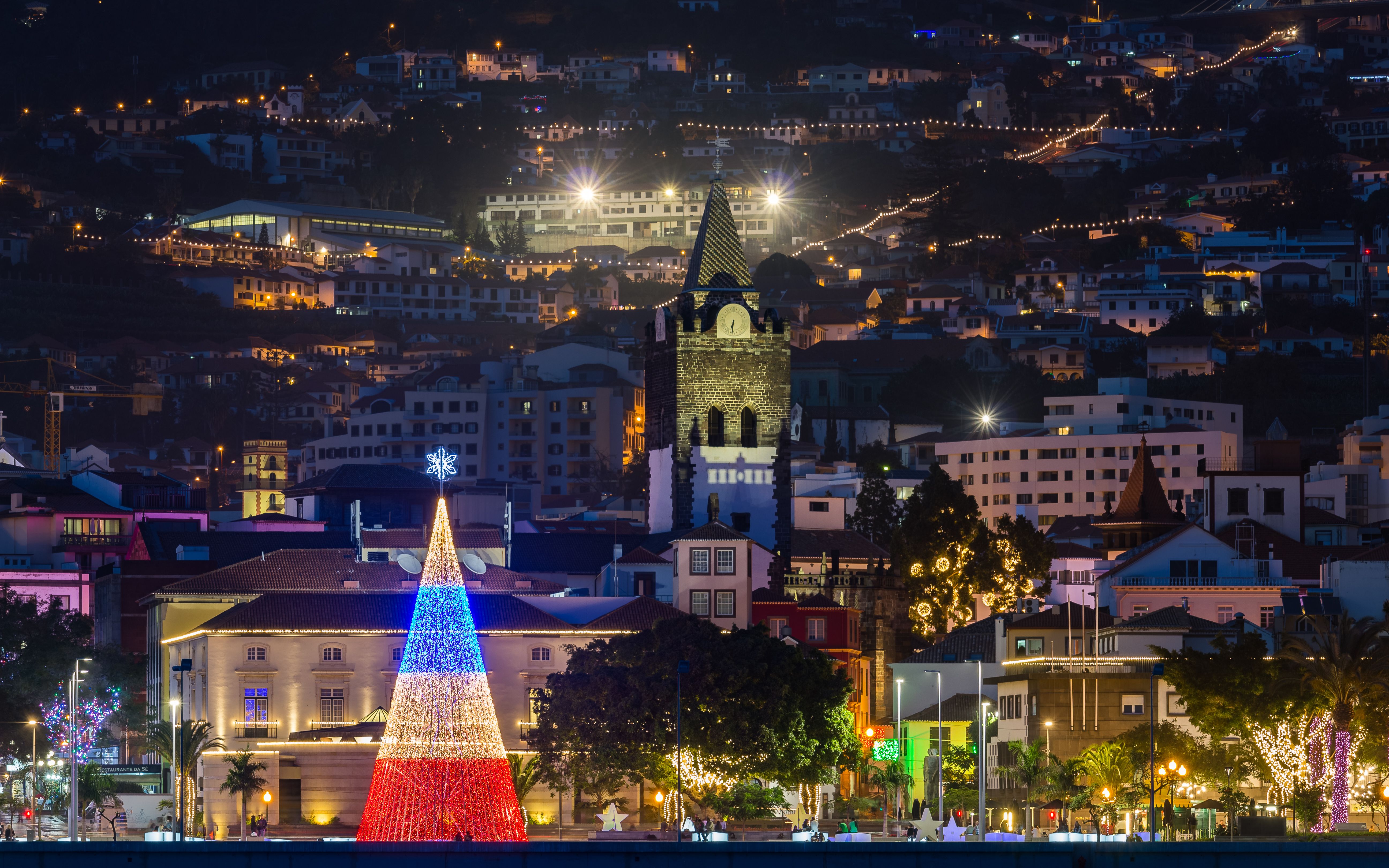 A view of Funchal city lit up at Christmastime in Madeira with an LED-lit Christmas tree