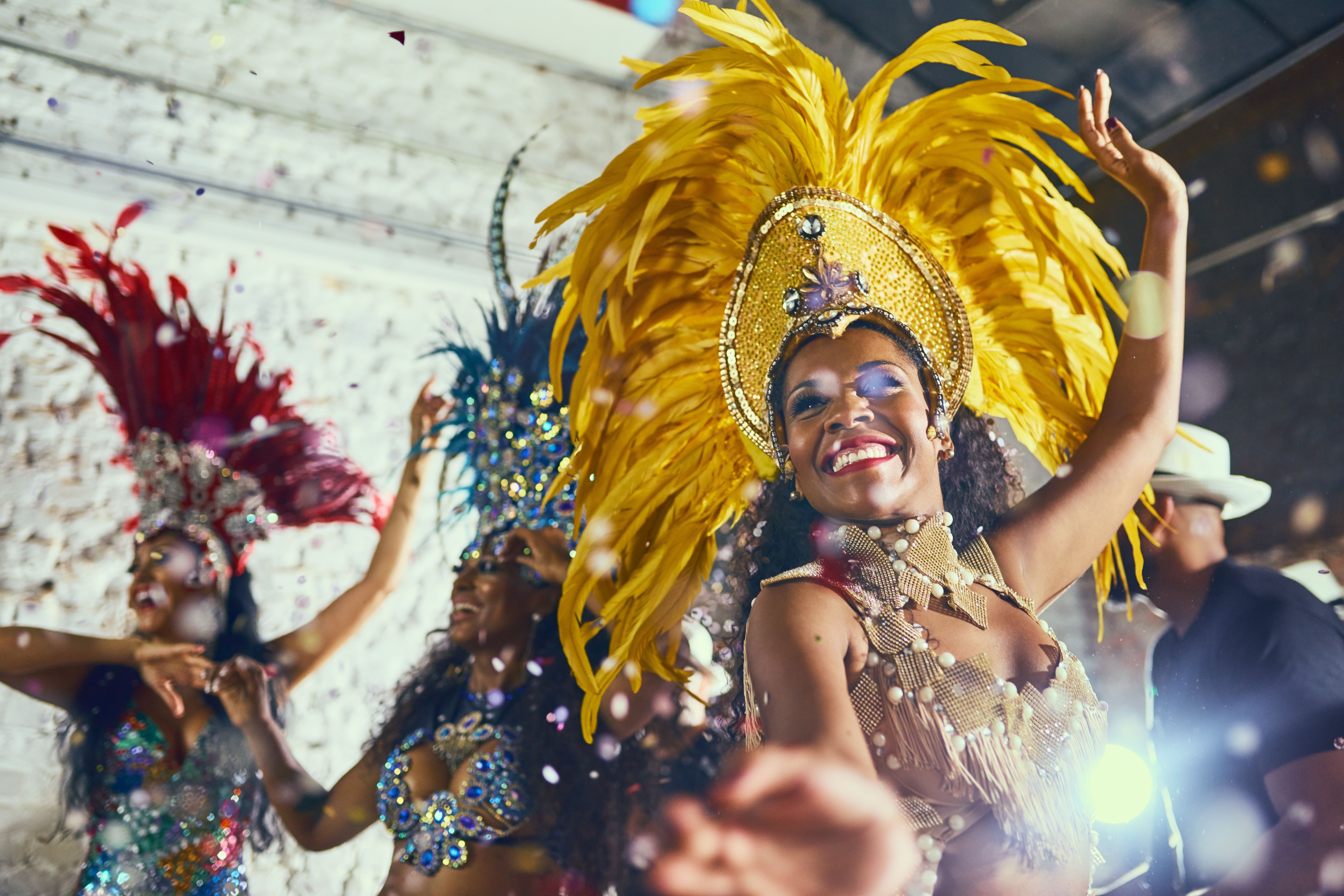 A close up view of Carnival dancers in a parade with bright coloured costumes and head dresses.