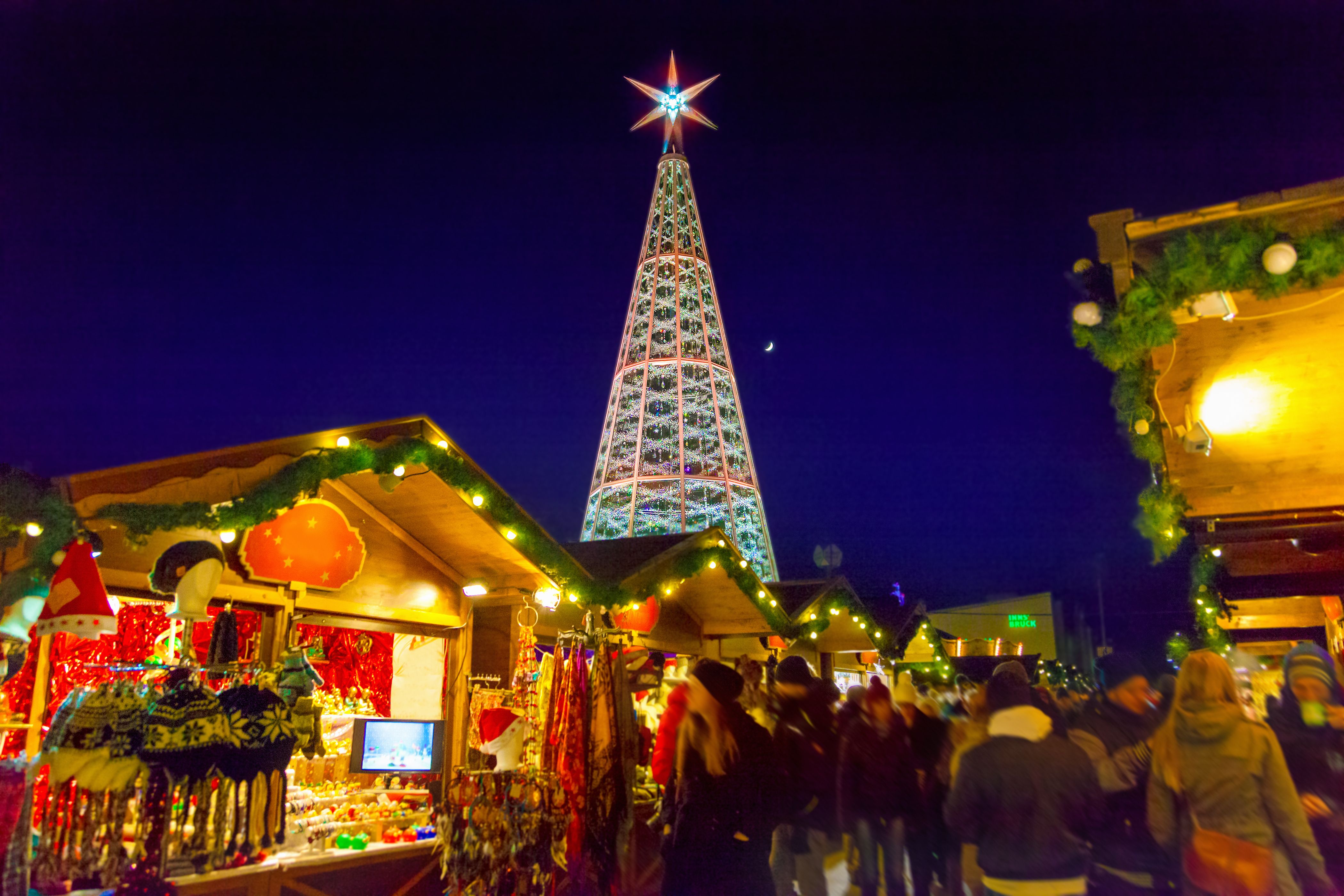 A close up shot of festive market stalls at Innsbruck Christmas market in Austria with an LED-light Christmas tree