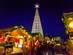 A close up shot of festive market stalls at Innsbruck Christmas market in Austria with an LED-light Christmas tree