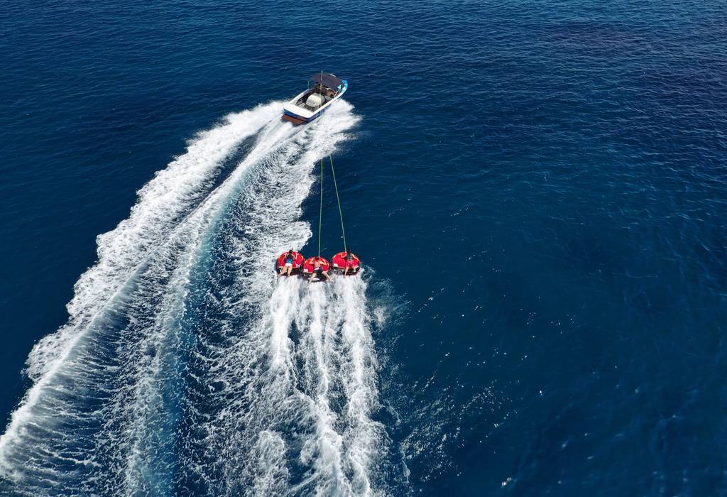 An aerial photo of extreme power boat donut water-sports cruising in high speed in deep blue open ocean bay