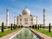 View of the white marble Taj Mahal on a sunny day with the building reflected in a shallow reflections pool in the landscaped gardens