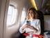 Female traveller using her phone on an airplane and looking through the window