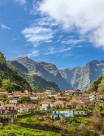 A view on traditional beige and yellow houses nestles among towering green mountains