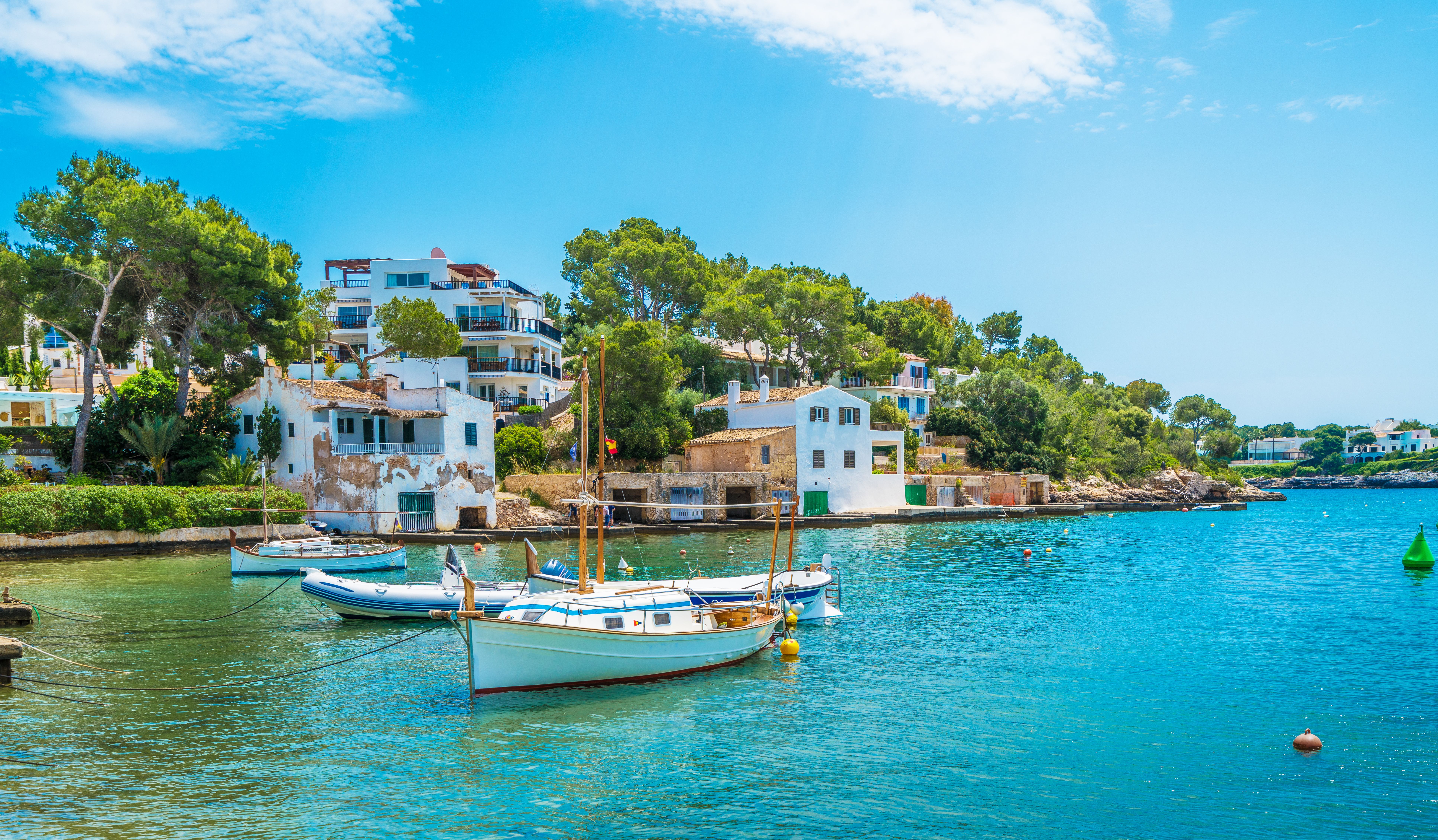View of Cala D'or town in Majorca with waterfront houses and sailing boats