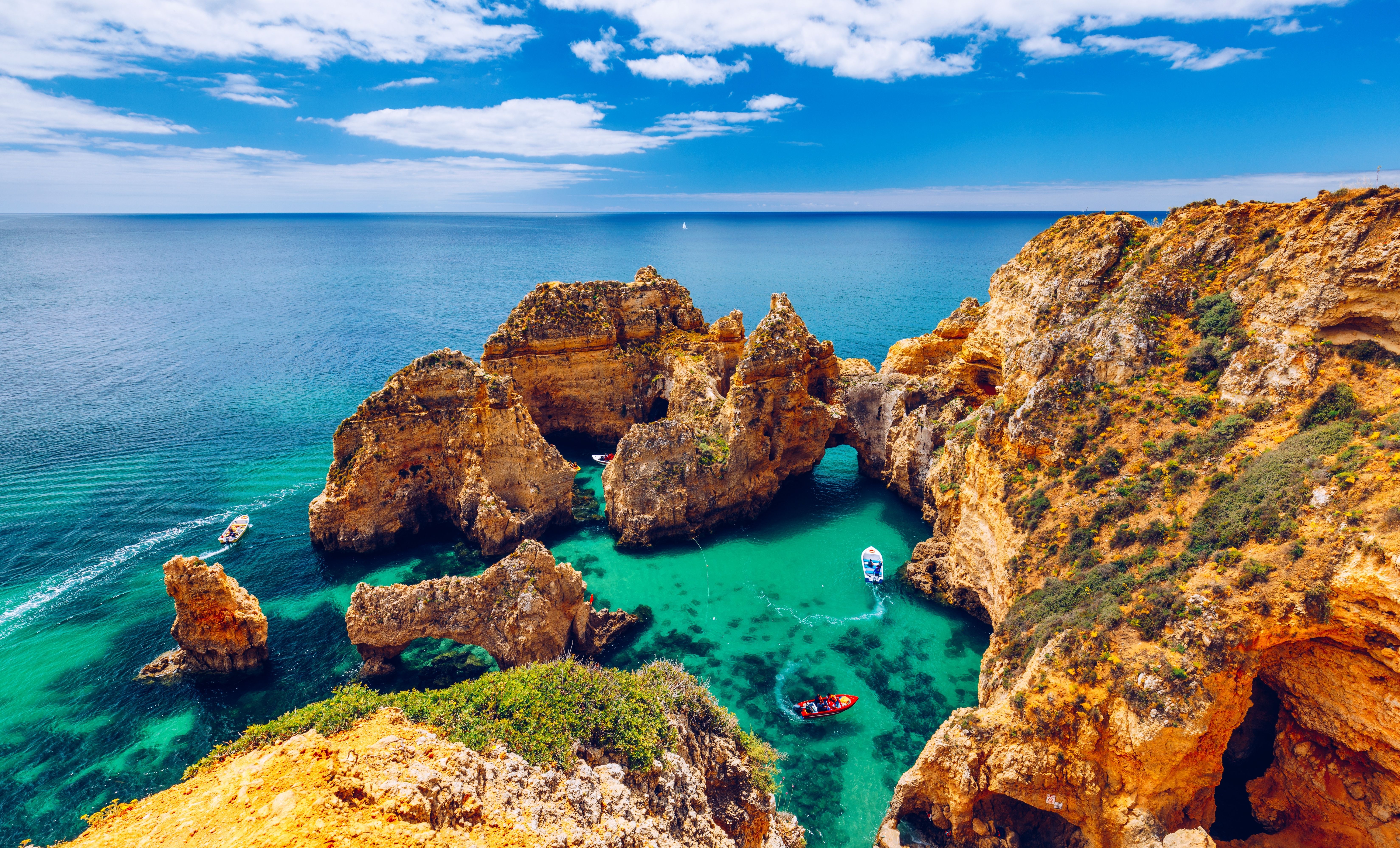 Aerial view of the Ponta da Piedade sea cliffs in Lagos, the Algarve, with motor boats exploring the caves