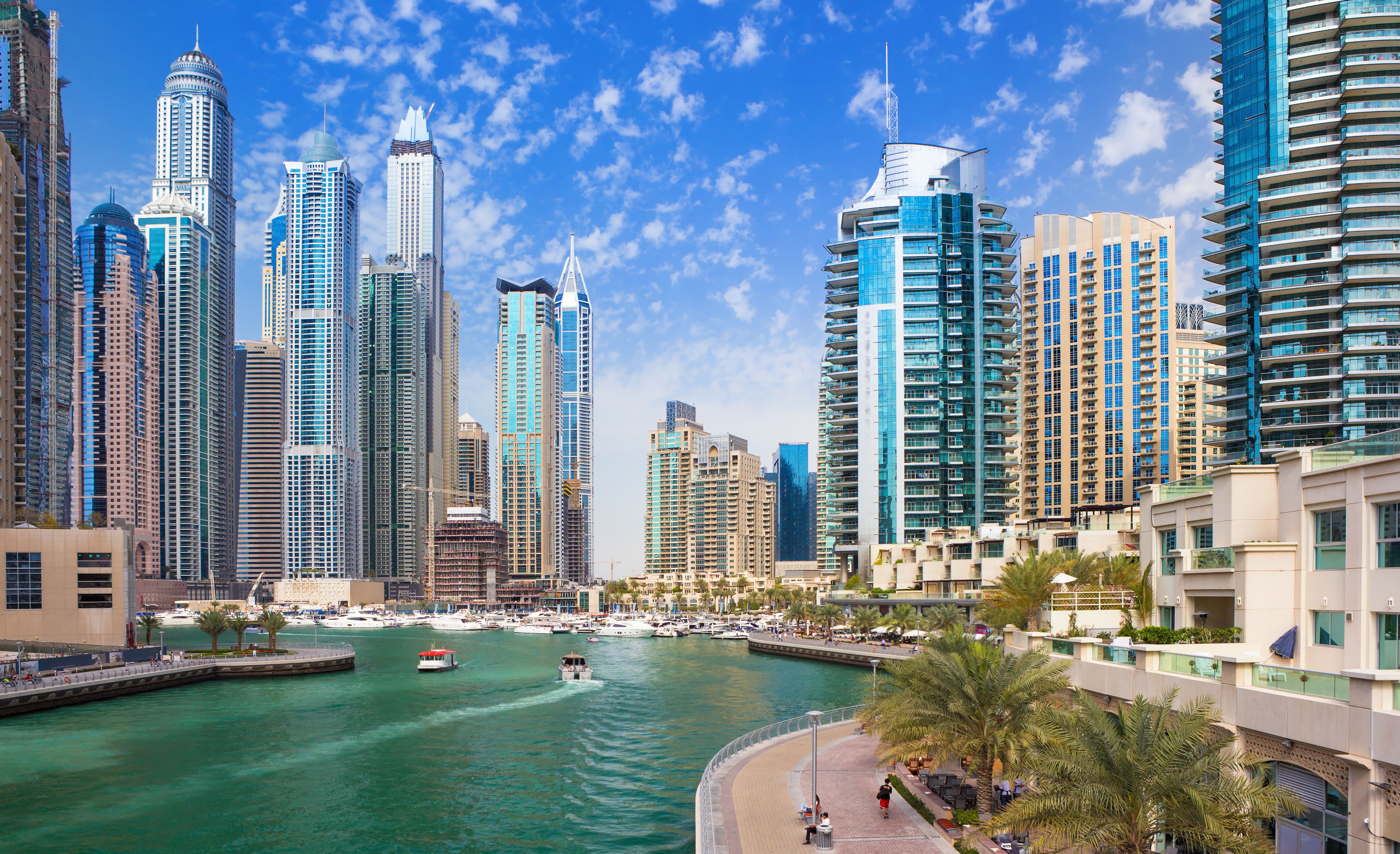 View of a boat travelling down the main canal of Dubai Marina surrounded by skyscraper buildings