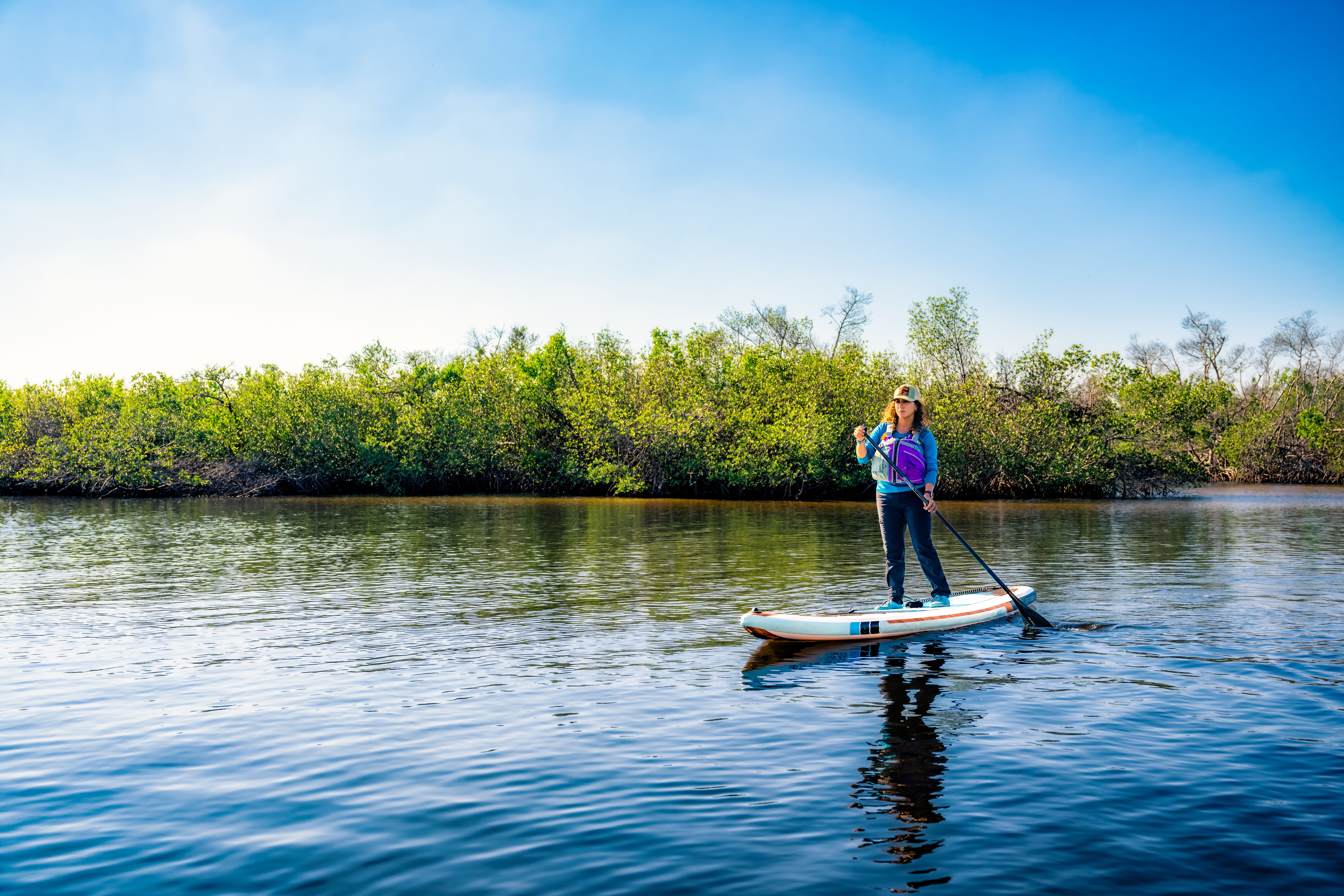 A woman on a stand up paddle board on a river in Florida