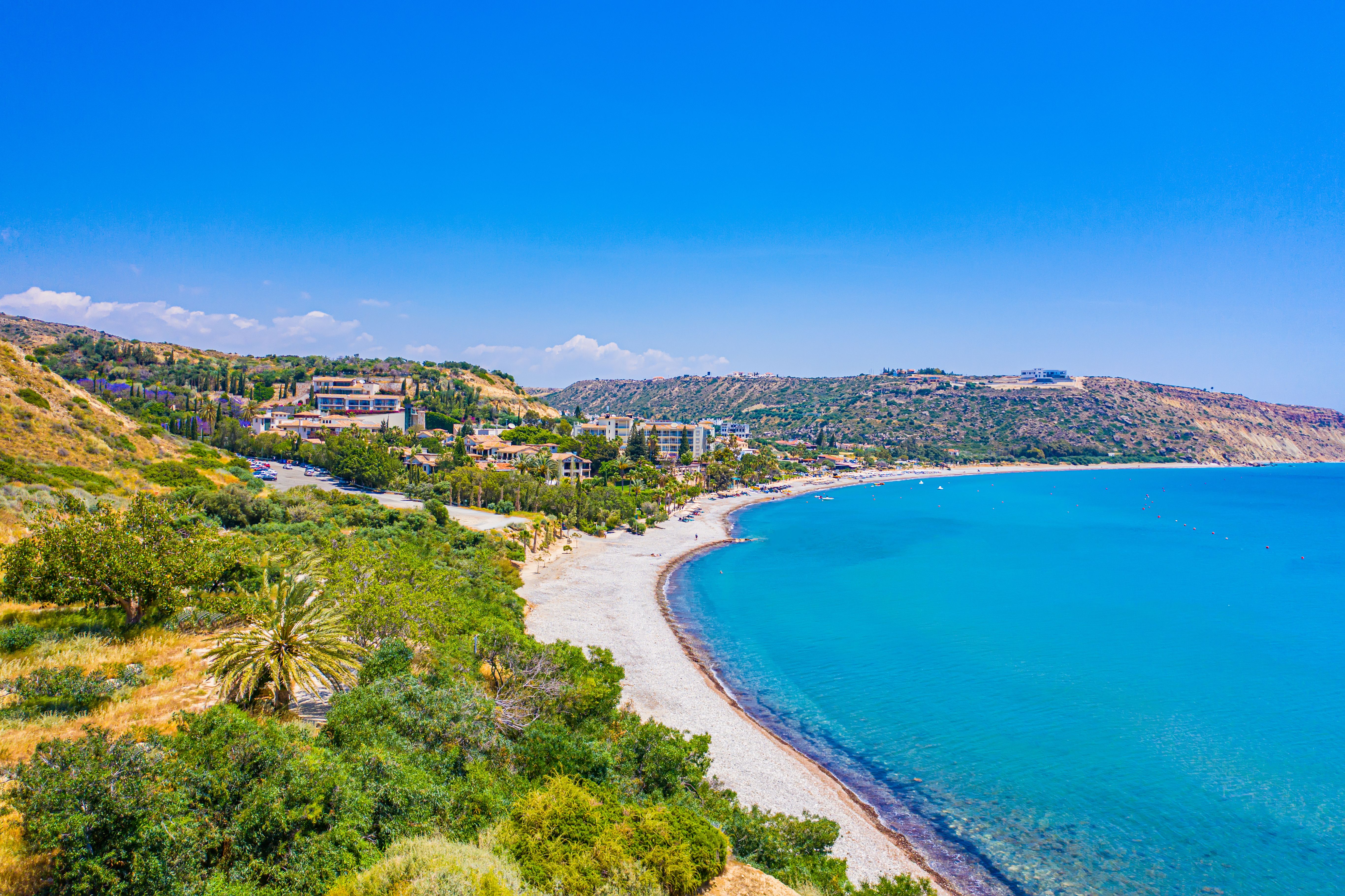 Aerial panoramic view of a sweeping beach lapped by bright blue waters in Cyprus