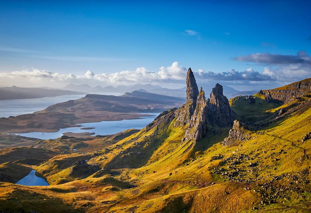 A sunset panorama of a dramatic rocky pinnacle known as the Old Man of Storr with lochs, seas and islands spreading out across the photo