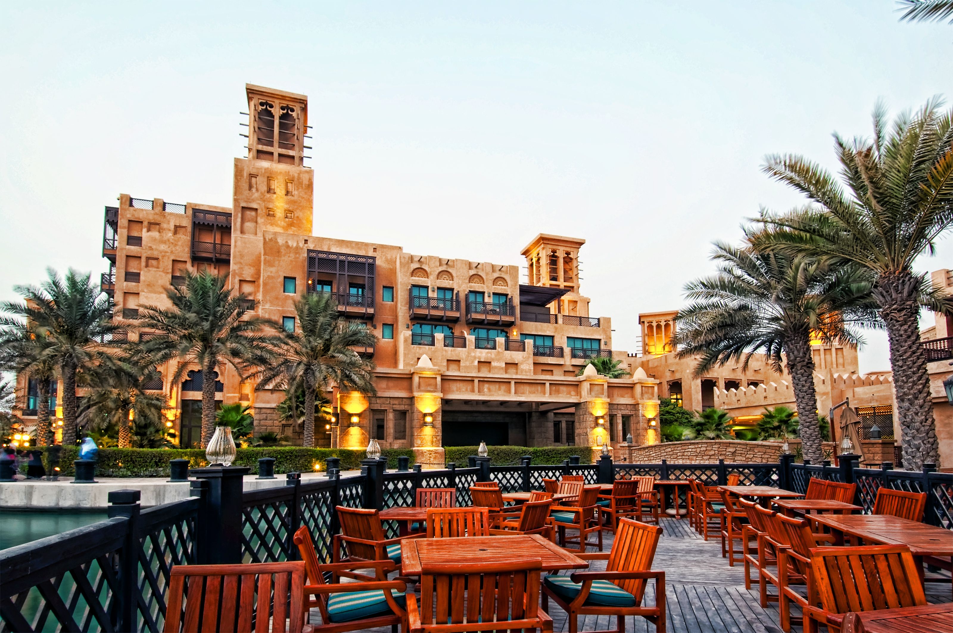 Outdoor restaurant tables in Dubai overlooking a grand hotel with palm trees