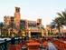 Outdoor restaurant tables in Dubai overlooking a grand hotel with palm trees