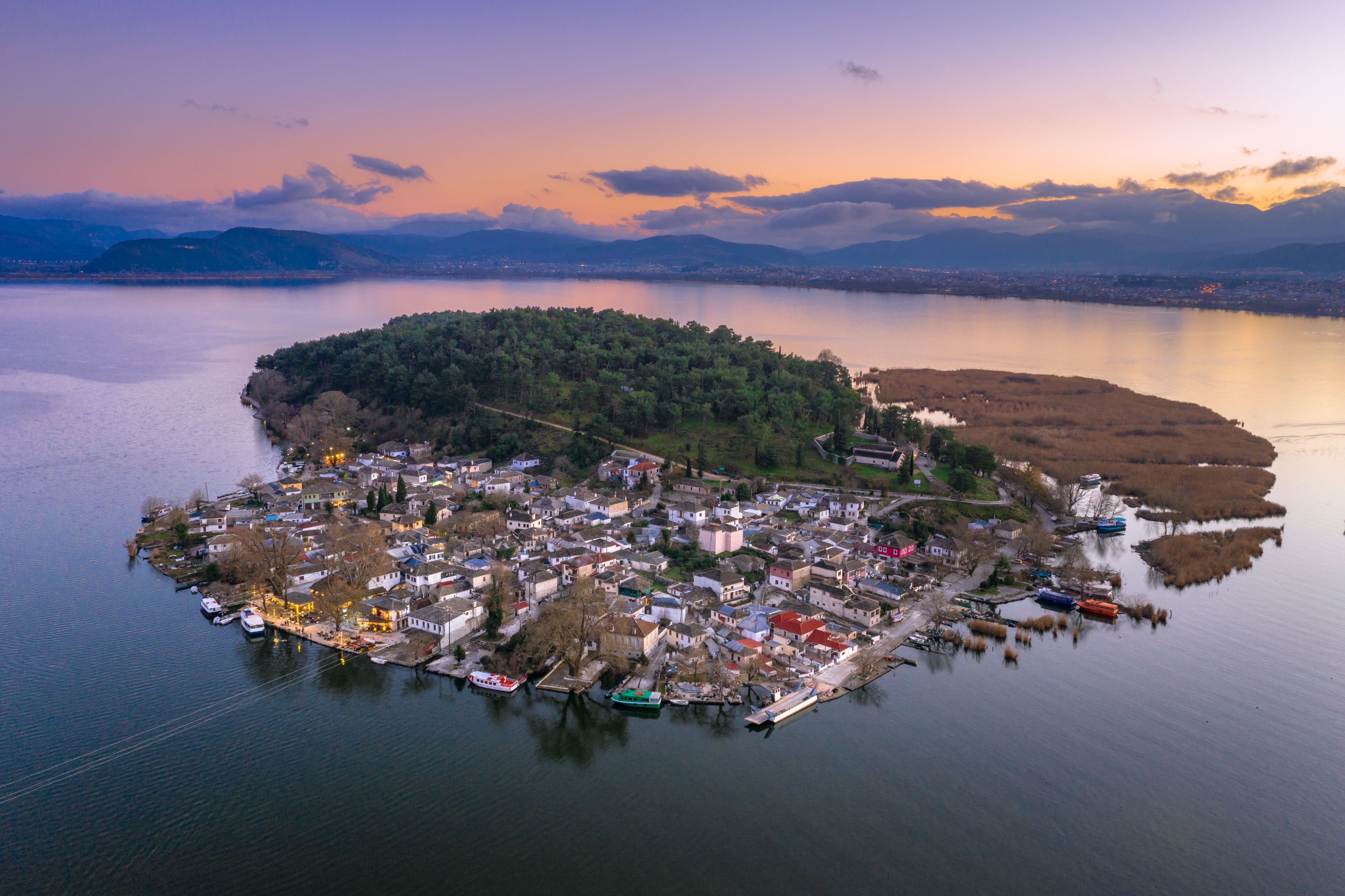 Aerial sunset view of a small island village in the middle of a still lake.