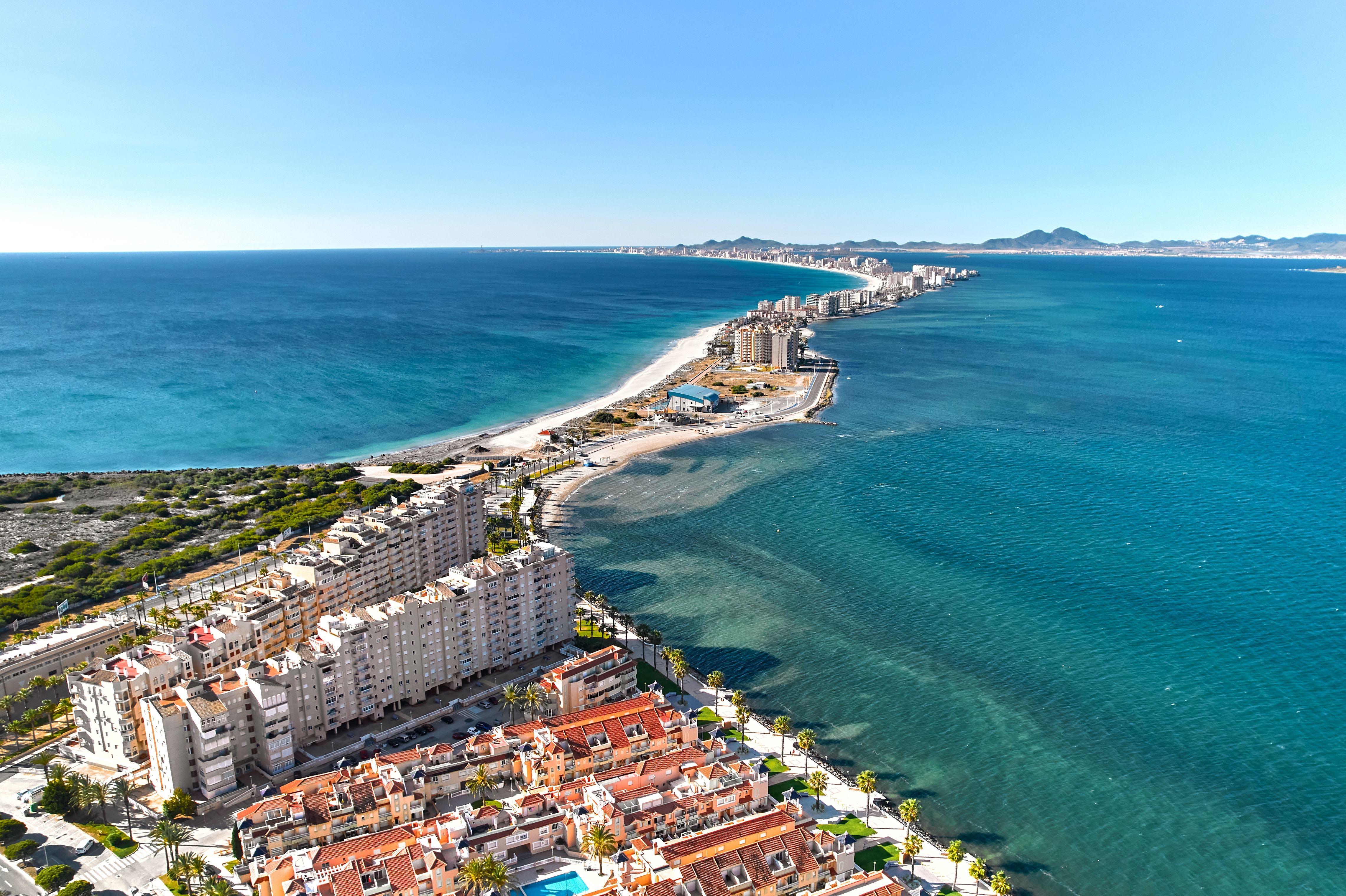Aerial view of high rise apartments and a huge hotel-lined sandbar in Spain.