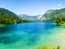 A view of the clear turquoise water of Lake Bohinj in Slovenia surrounded by verdant valley mountains