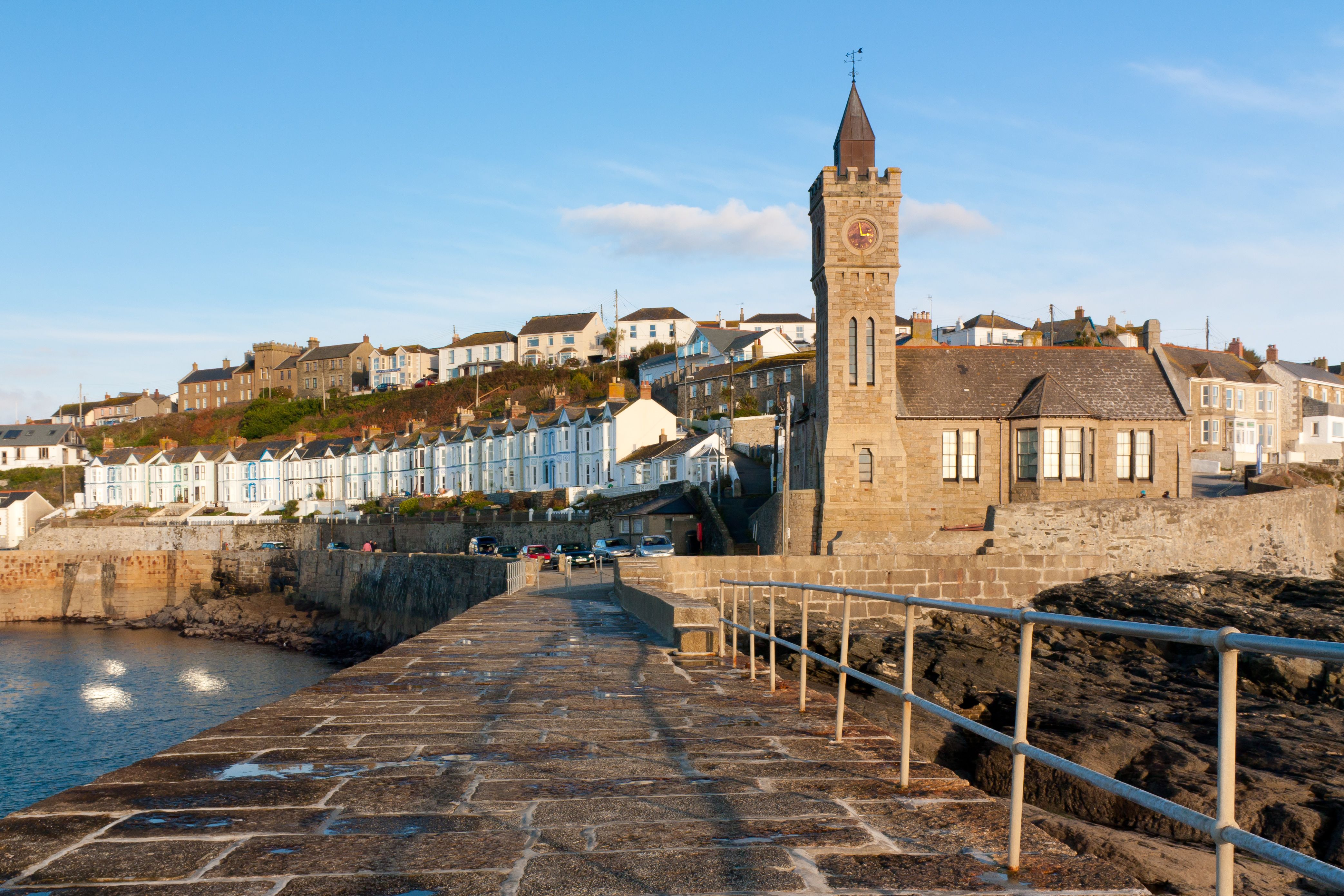 View across a paved pier towards a quaint seaside town with a small church at one end.