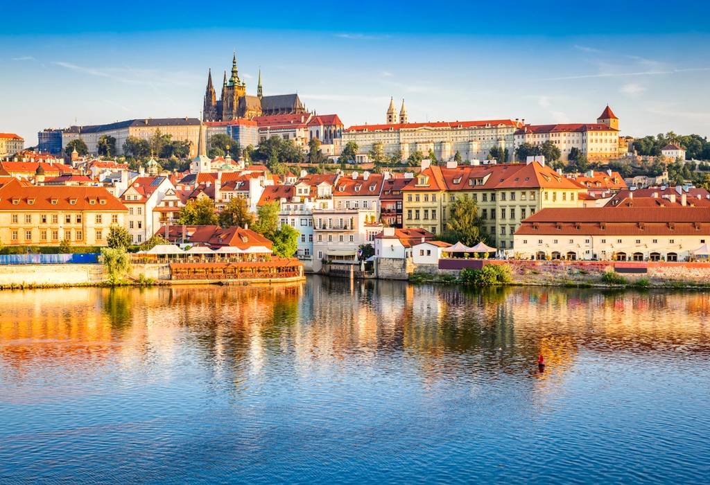 River view of Prague city on a bright day with Praha Castle in the distance