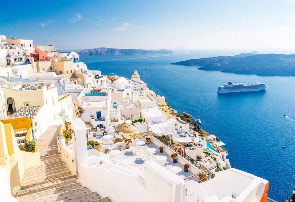 Aerial view of the whitewashed buildings of Fira overlooking the deep blue waters of Santorini's caldera