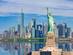A view across the water of New York's skyline with the Statue of Liberty in the forefront and the Empire State Building in the background