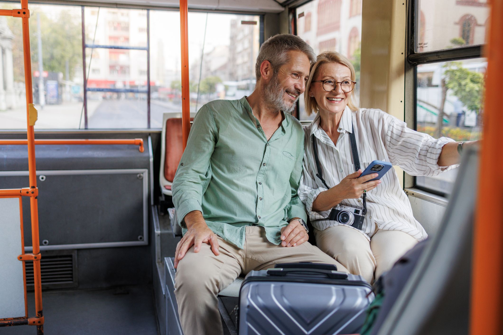Mature couple enjoying a city bus ride, sharing smiles and looking relaxed.