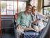 Mature couple enjoying a city bus ride, sharing smiles and looking relaxed.