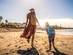 Mother and son walking on the sandy beach as the sun sets