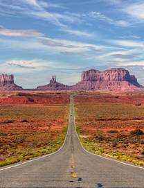 Landscape view of road leading towards the dramatic red rock formations of Monument Valley