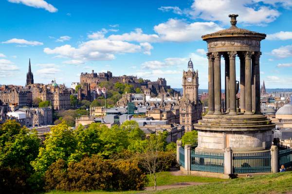 View of a columned monument and the skyline of Edinburgh, including its castle, from a Calton Hill