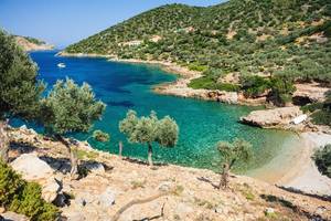A picture of Agalou Laka beach on the west side of the Greek island of Alonissos located in the Aegean Sea with rugged landscape and beautiful sandy beach and clear water