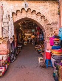 A brick arch covered in colourful rugs and texitles that leads to more markets in Marrakech's medina