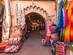 A brick arch covered in colourful rugs and texitles that leads to more markets in Marrakech's medina