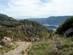 Two women and a child hiking along a greenery-surrounded trail towards the coast beyond