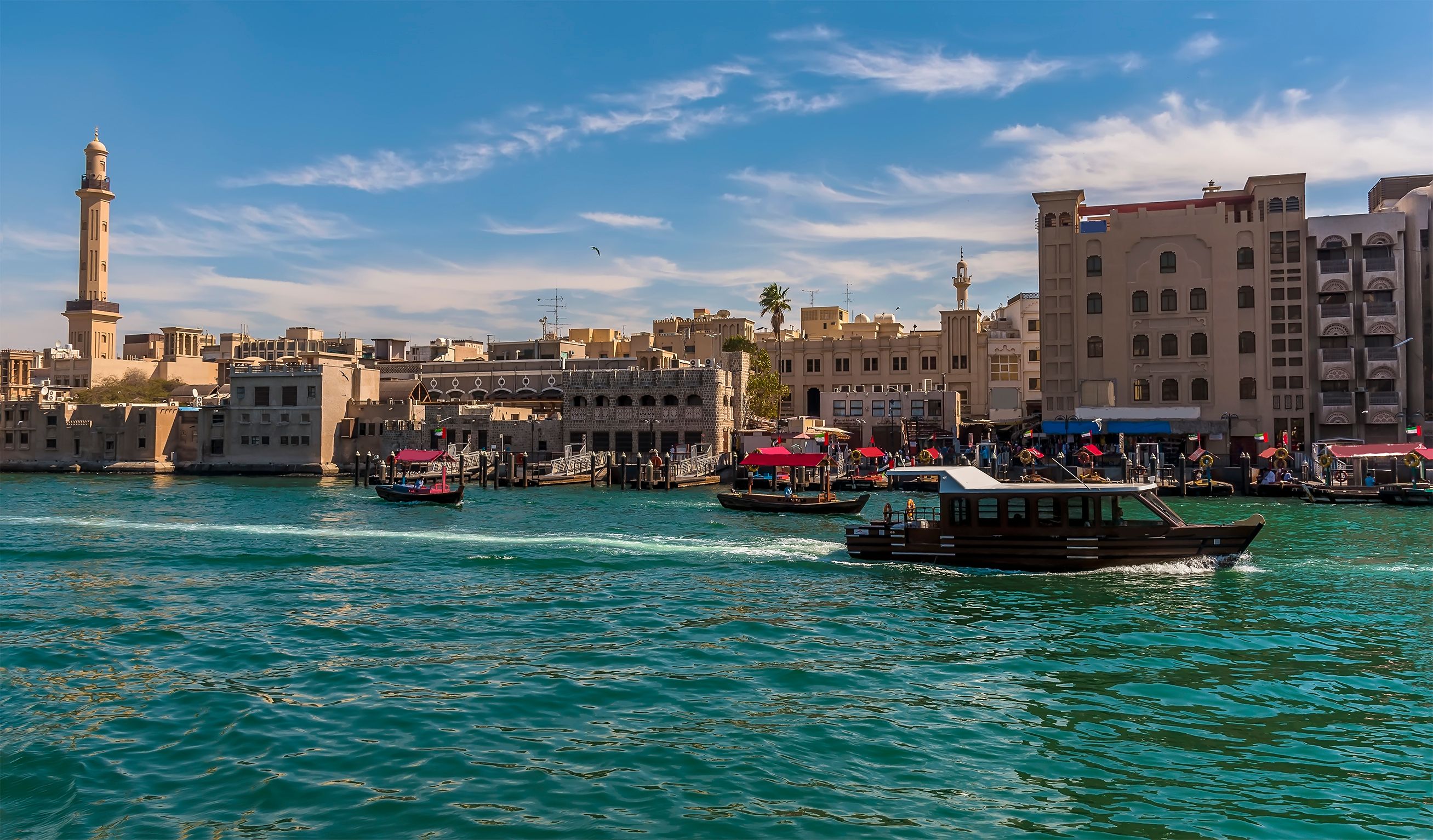 A view of Dubai Creek in the Al Fahidi district with colourful ferry boats on a bright blue day