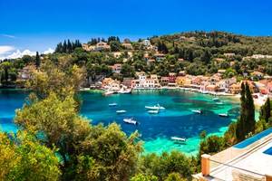 A picturesque image of Loggos village and small port filled with small boats in Paxos, an Ionian Island of Greece