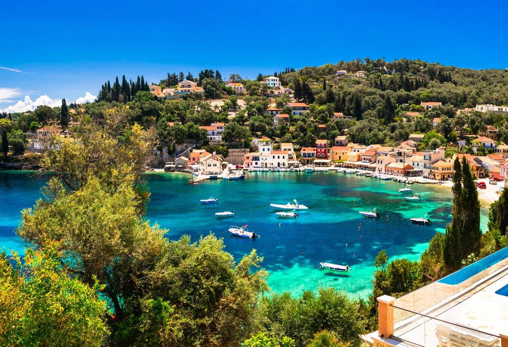 A picturesque image of Loggos village and small port filled with small boats in Paxos, an Ionian Island of Greece