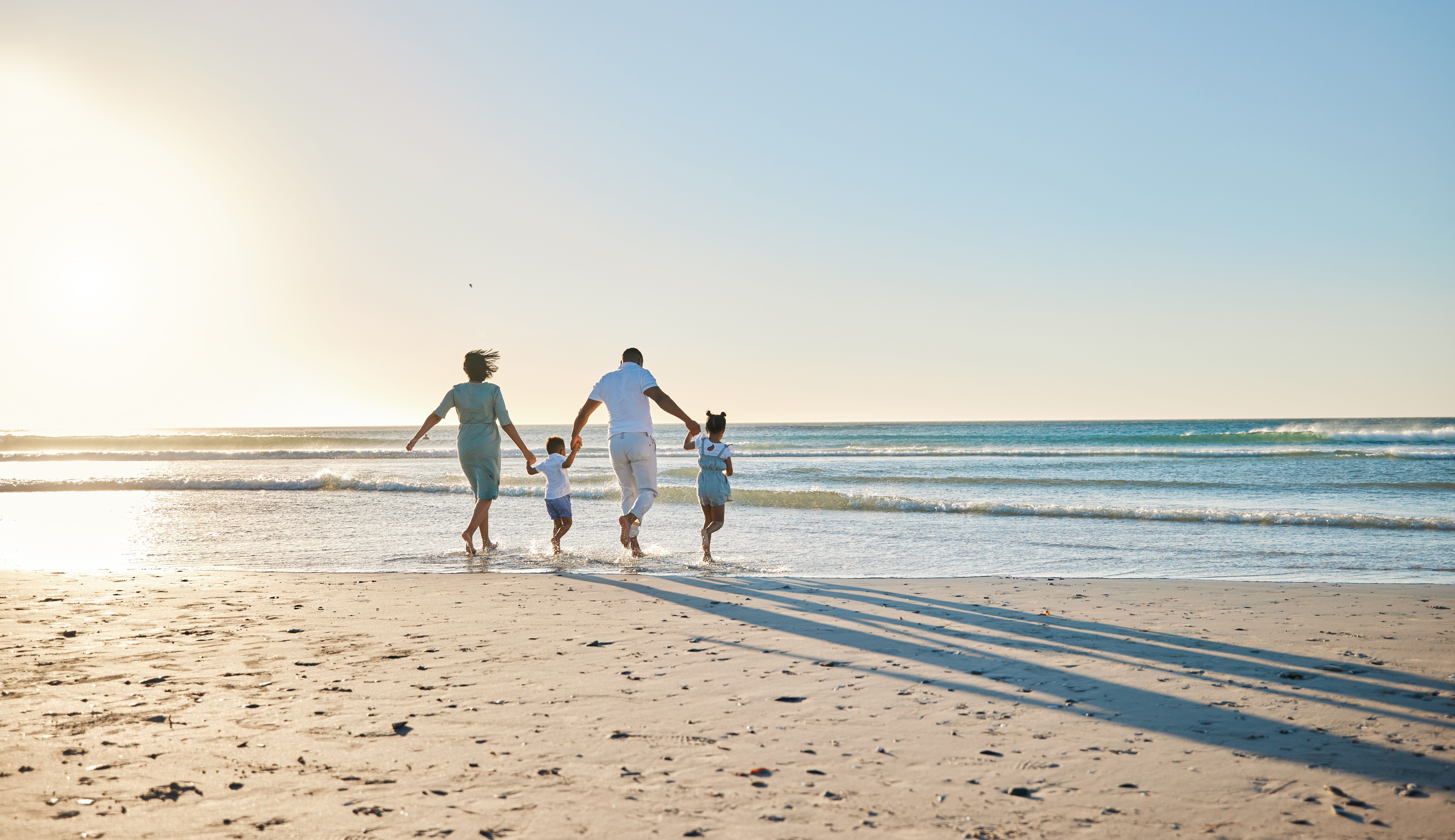 Rearview shot of a happy family walking towards the sea on a beach