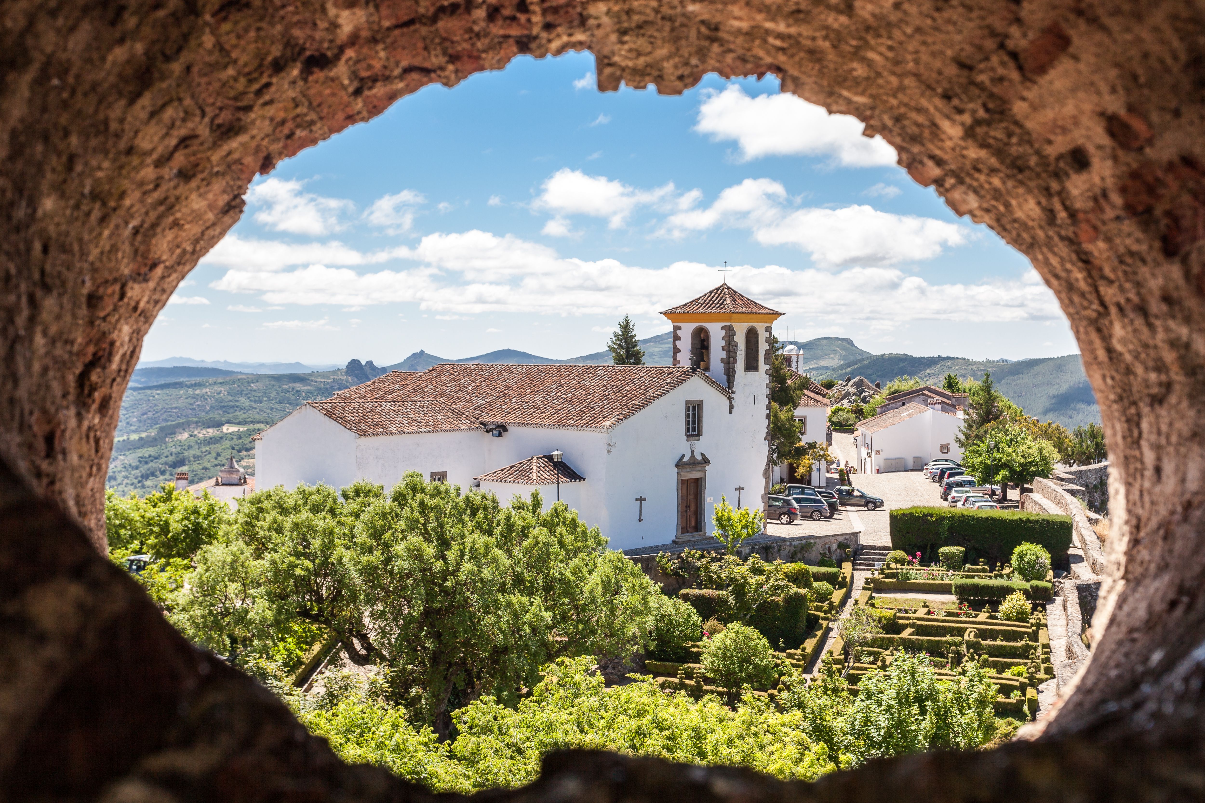 View of the whitewashed Santa Maria Church framed by a stone wall on a bright day