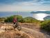 A woman mountain biking on a coastal trail above the mediterranean sea in Tuscany, Italy